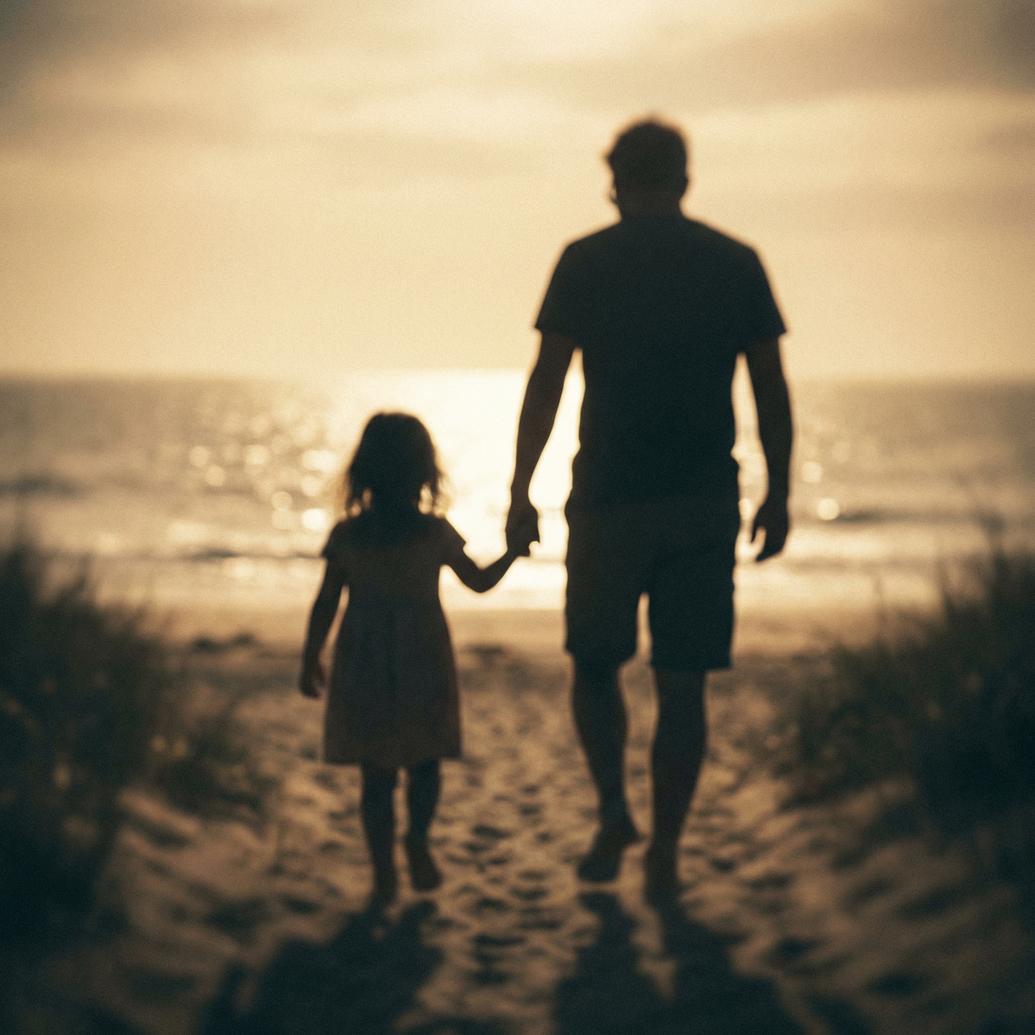 Father and daughter walking on the beach at sunset